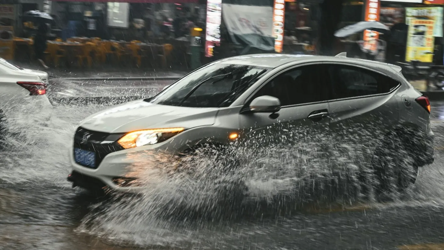 Vehicle splashing through water on wet road in tropical rain. (Photo: C Joyful/Unsplash)