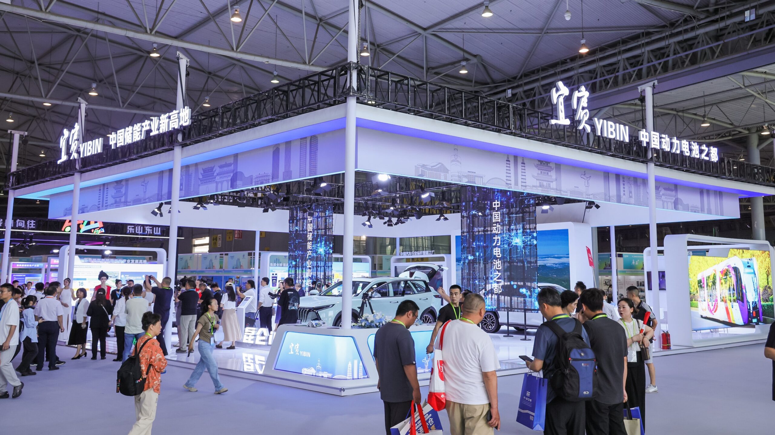 A brightly lit exhibition pavilion for Yibin at CAPAS Chengdu, branded as the "Capital of Power Batteries in China," featuring electric vehicles and interactive displays of battery technology. Image/Photo Credit: Messe Frankfurt