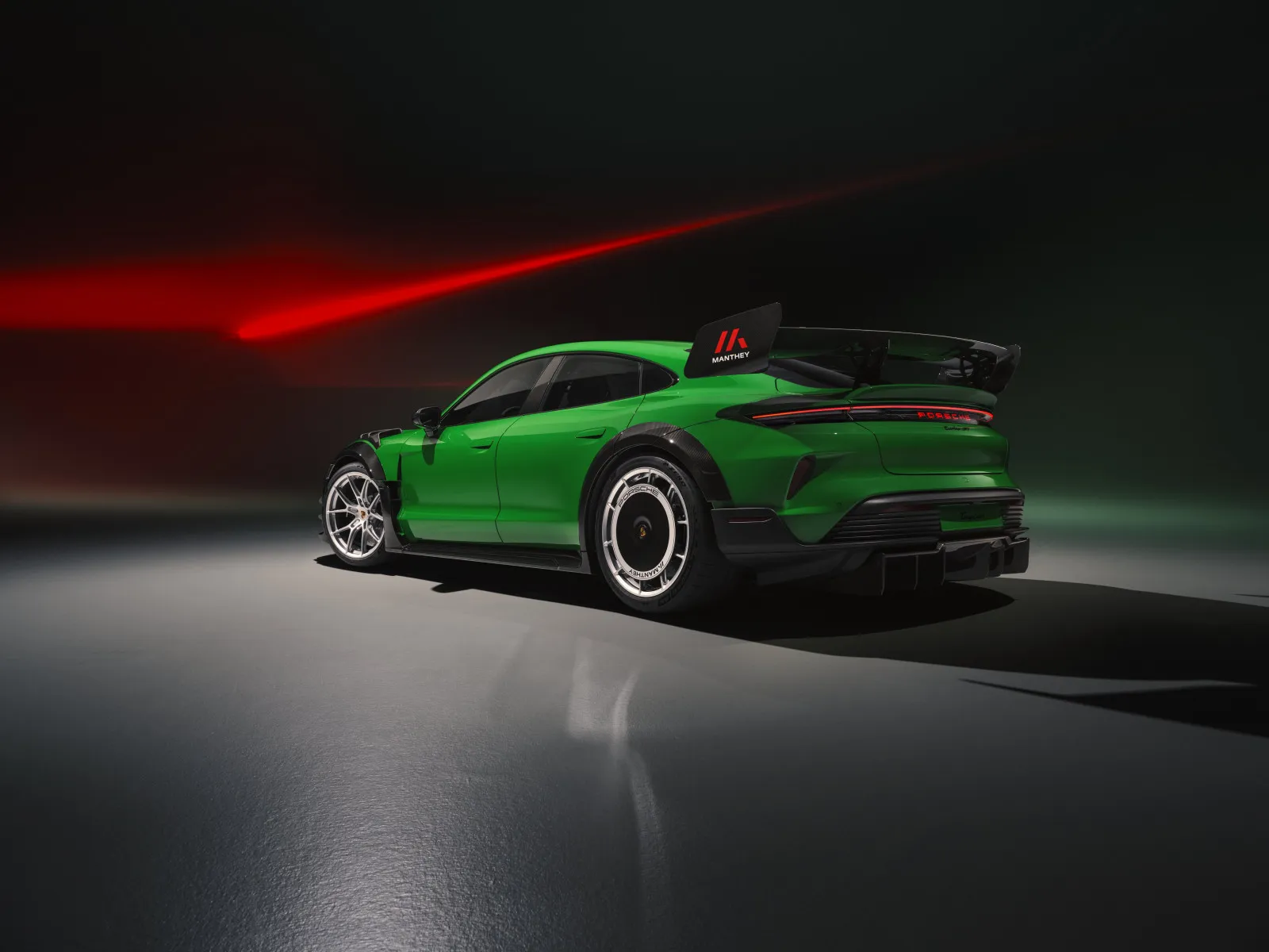 A high-performance bright green Porsche Taycan Turbo GT equipped with a prominent black carbon fiber Manthey rear wing winglet. (Photo: Pirelli)