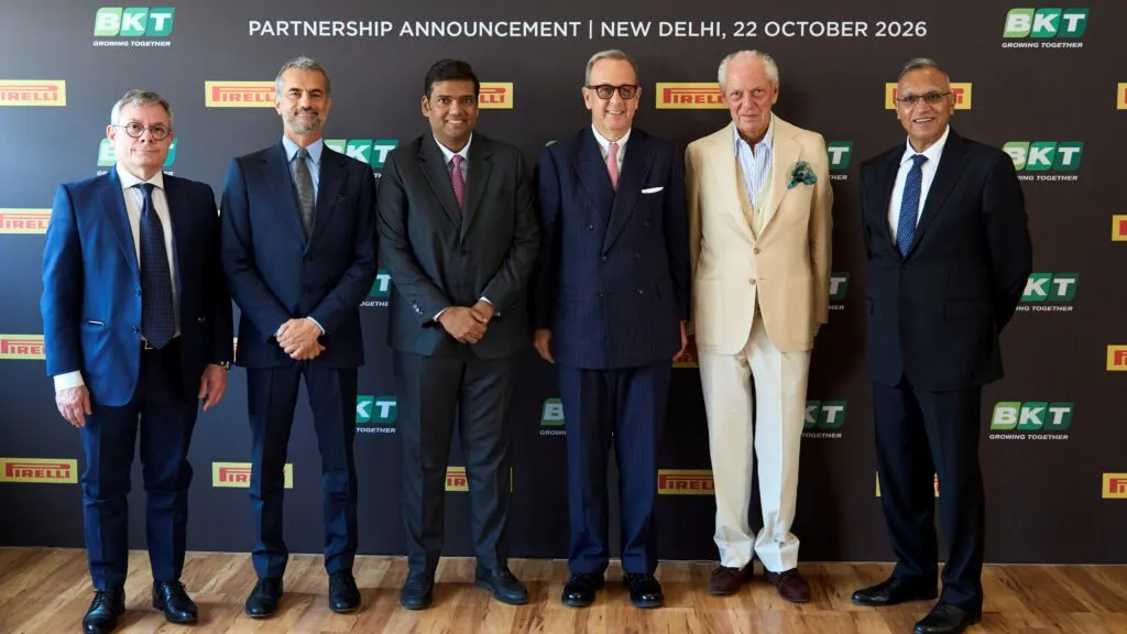 Executives from BKT and Pirelli, including Marco Tronchetti Provera and Rajiv Poddar, standing in a line against a backdrop displaying BKT and Pirelli logos during a partnership announcement in New Delhi.